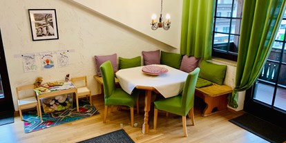 Hundehotel - Garmisch-Partenkirchen - Wohnzimmer Appartement Azalea mit Essecke und Kinderspiel & -maltisch - Appartement Azalea