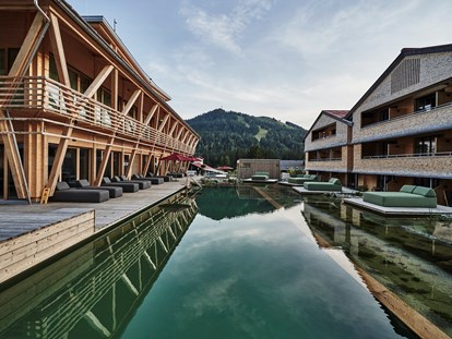 Hundehotel - Pools: Außenpool nicht beheizt - Bayern - Außenbereich des Hotel HUBERTUS und seinem Wellnessbereich Mountain Spring Spa mit NaturBadeSee - HUBERTUS MOUNTAIN REFUGIO ALLGÄU
