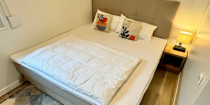 Hundehotel - Mikrowelle - Österreich - Im Schlafzimmer 1 befindet sich ein Kingsize Bett (180cm), ein Arbeitsplatz sowie große Schränke. Darin findest du auch einen Staubsauger, Wäscheständer sowie Bügeleisen und Bügelbrett. - Blue Flamingo Lake Lodge 