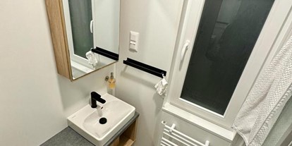 Hundehotel - Unterkunftsart: Bungalow - Österreich - Im Badezimmer befinden sich ein Spiegelschrank, Fön und ein Heizkörper für Handtücher. - Blue Flamingo Lake Lodge 