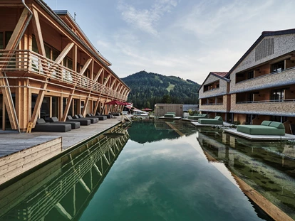 Hundehotel - Pools: Außenpool beheizt - Lech - Außenbereich des Hotel HUBERTUS und seinem Wellnessbereich Mountain Spring Spa mit NaturBadeSee - HUBERTUS MOUNTAIN REFUGIO ALLGÄU