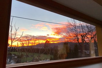 Ferienhaus mit Hund: Sonnenuntergang beobachtet durch das Wohnzimmerfenster - Ferienhaus Sausalblick 