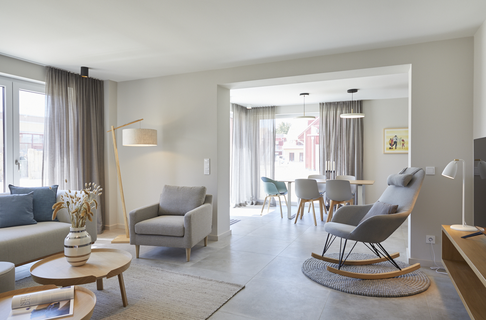 Hundehotel - Terrasse - Mecklenburg-Vorpommern - Entspannen Sie in unserem offenen Wohnbereich mit Essnische: Bequeme Sofas, Schaukelstuhl, moderner Couchtisch und Balkonzugang laden zum Wohlfühlen ein – ideal für Familien oder Paare in Bades Huk. - Bades Huk