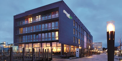 Hundehotel - Klassifizierung: 3 Sterne S - Schleswig-Holstein - Blick auf das StrandGut Resort abends - StrandGut Resort