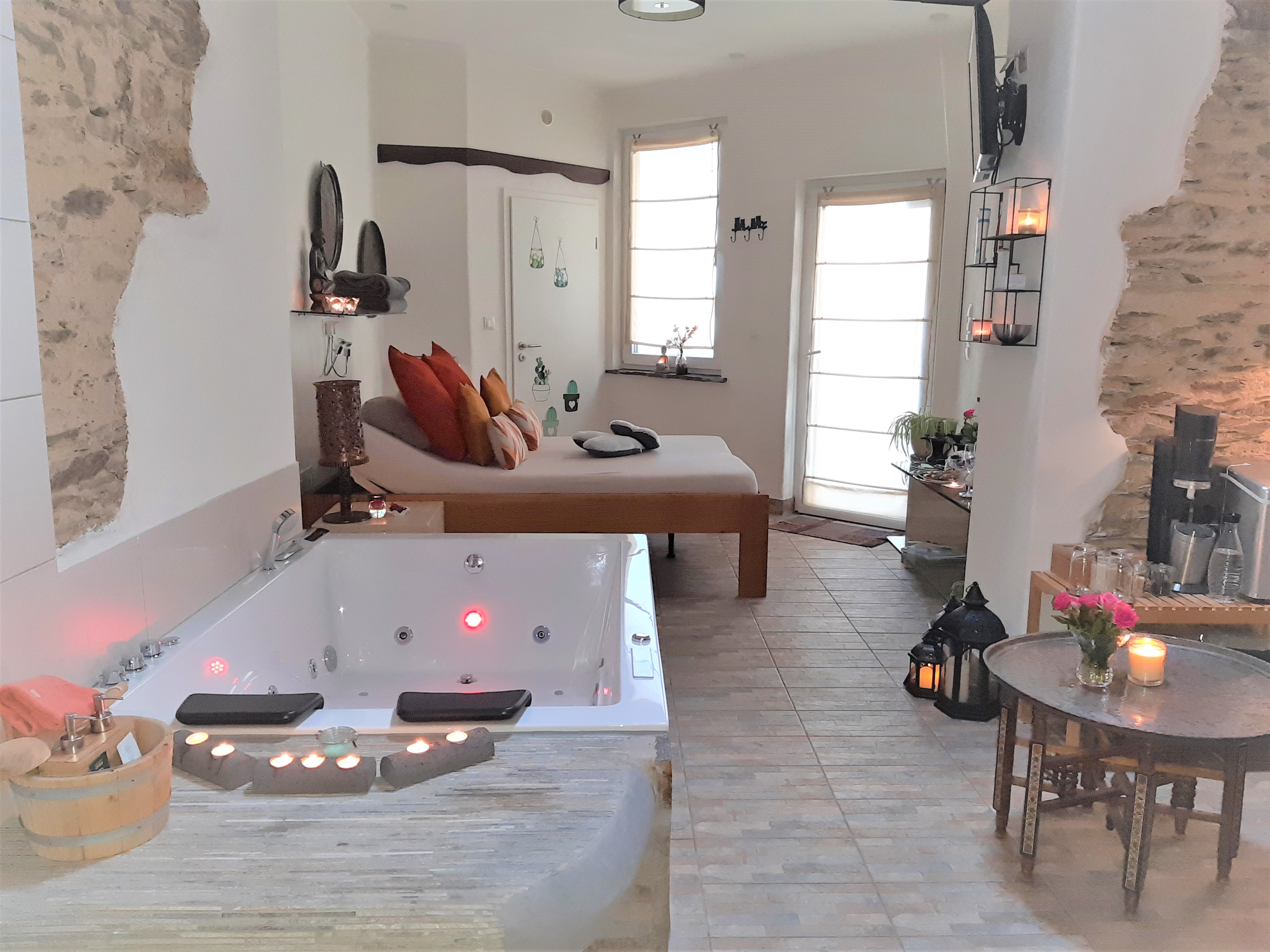 Urlaub-mit-Hund: Doppel-Whirlwanne im Spa. Rechts hinter dem Tisch: Getränke-Ecke mit gratis Kaffee, Tee und Mineralwasser. Im Hintergrund: Neben den beiden Doppel-Schlafzimmern im Ferienhaus gibt es ein weiteres roamntisches Doppelbett im Spa. - Wellness-Ferienhaus Maifelder Uhlenhorst - Wo die Fellnase mit in dem Privat-Spa darf